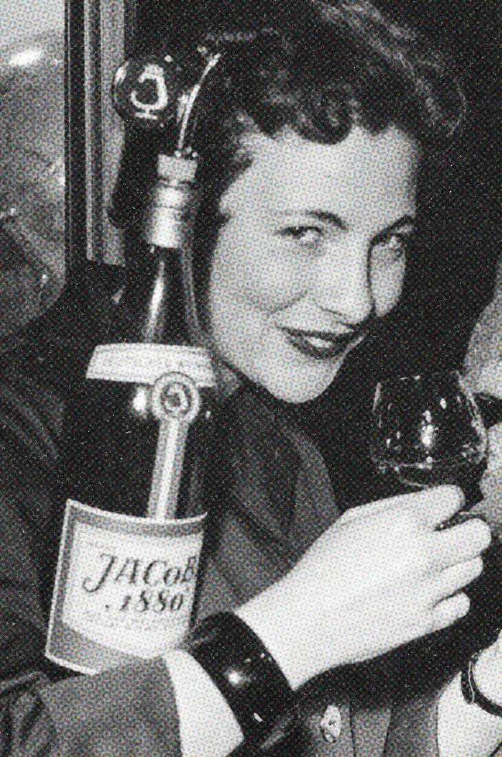 Frau im Stil der 1950er Jahre mit einer Flasche JACoBI 1880