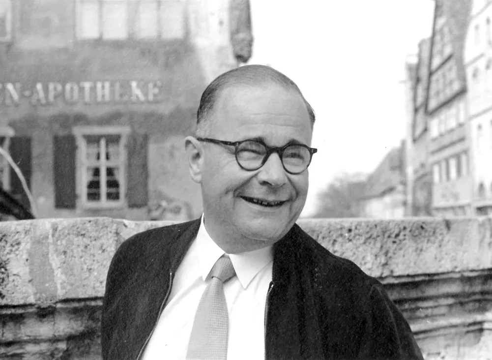 Lächelnder Herr mit Brille vor einer Apotheke, historisches Porträt