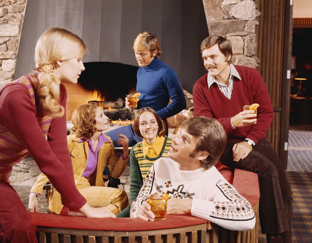 Freunde im Stil der 1970er Jahre mit Drinks am Kamin